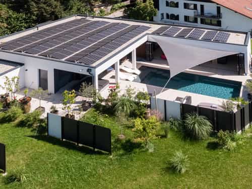 Schräge Luftaufnahme des Bungalows der Familie Eder mit Photovoltaik, Pool und Garten mit Sichtschutz