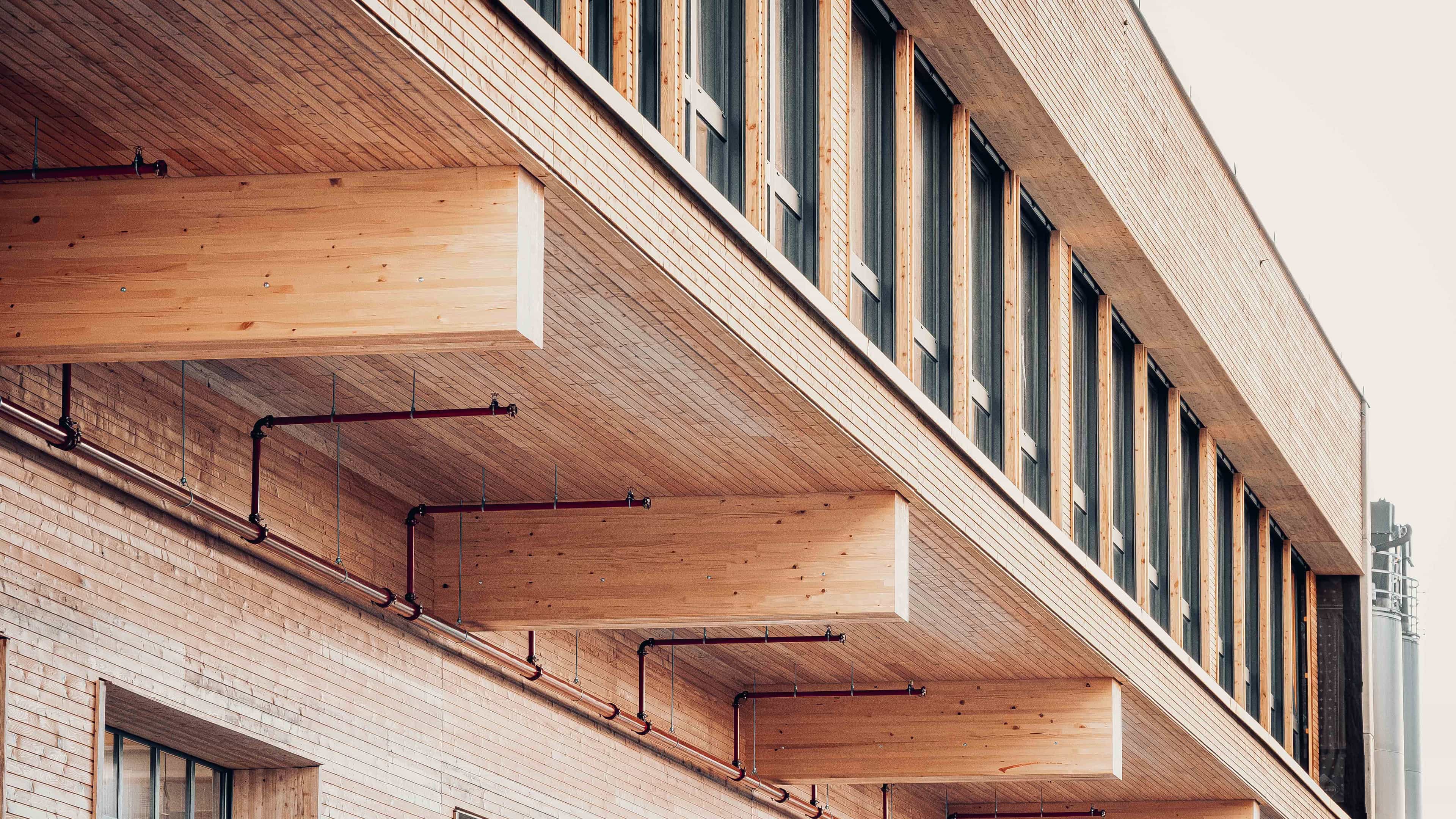 Detail der Dachuntersicht mit sichtbaren Holzträgern über der Holzfassade auf der Baustelle Wallstabe