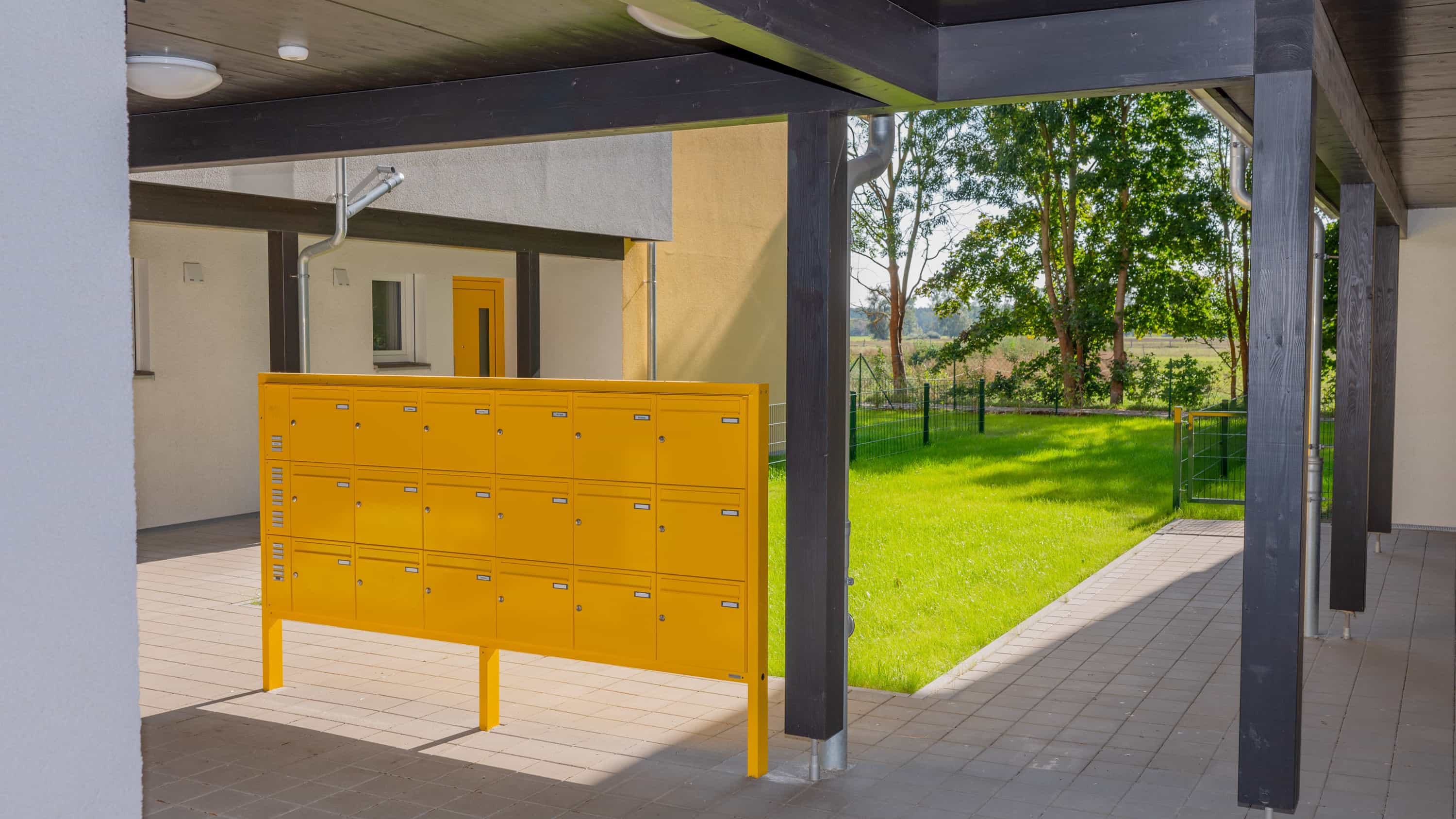 Gelbe Briefkastenanlage im überdachten Eingangsbereich eines Mehrfamilienhauses im Quartier Zum Glück Bötzow