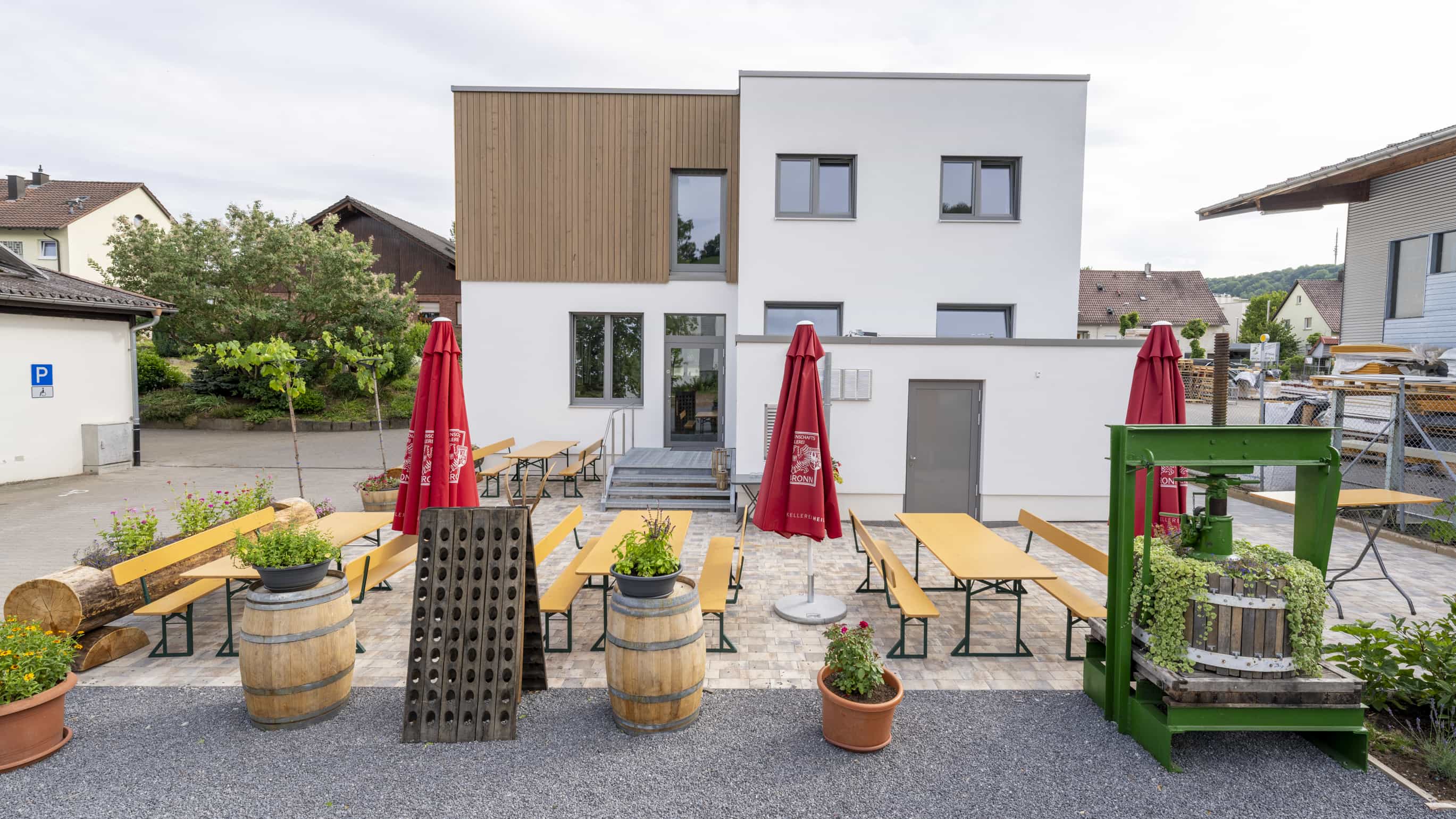 Außenterrasse der Weinwirtschaft Burgblick mit Biertischgarnituren, Weinfässern und alter Weinpresse