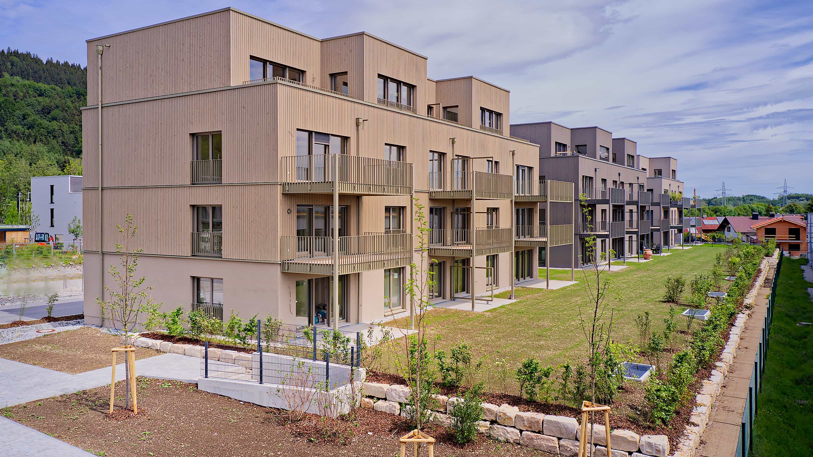 Mehrgeschossiges Mehrfamilienhaus mit Holzfassade und Balkonen im Mehrgenerationen-Wohnquartier Pfaffenwinkel