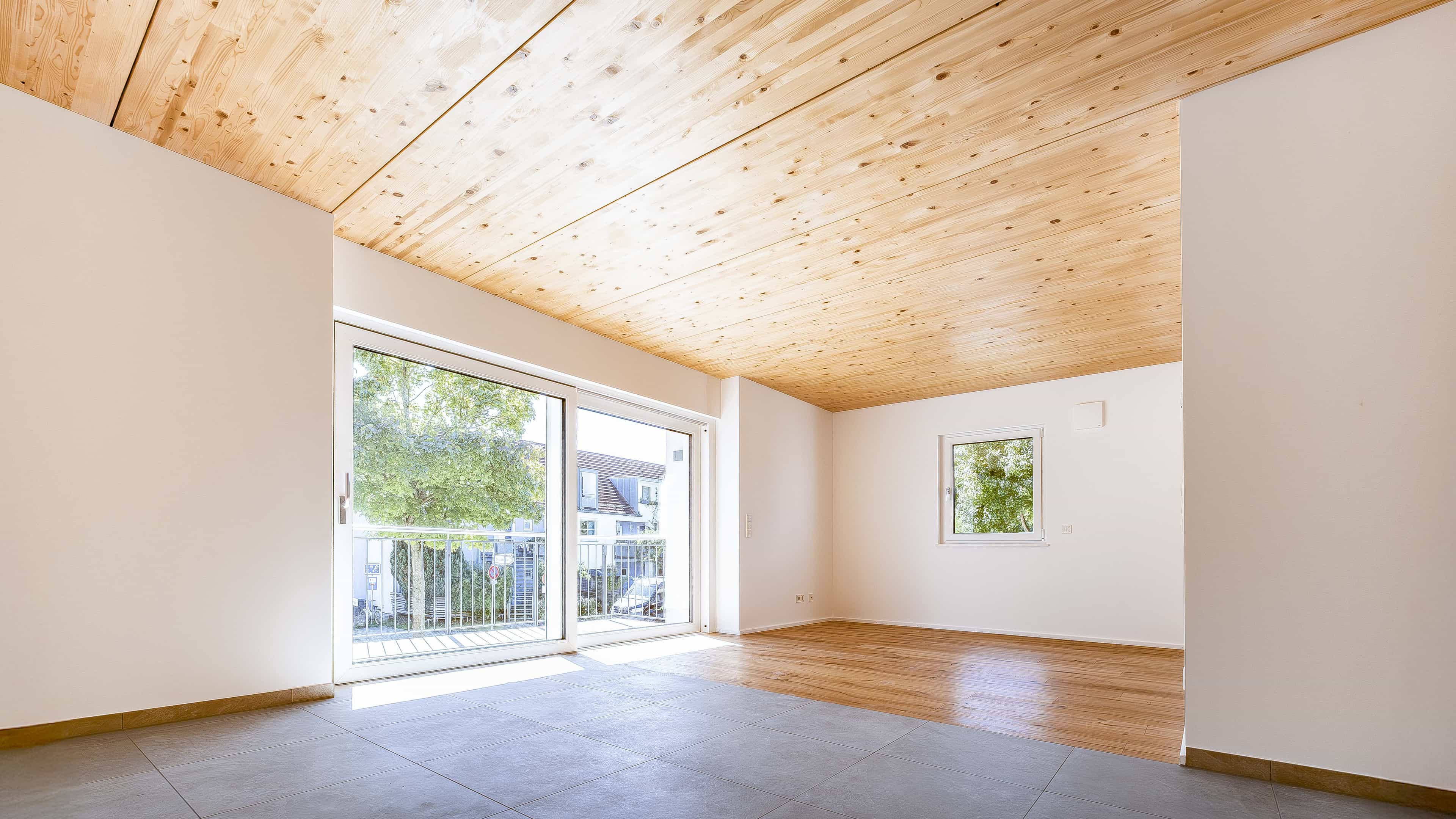 Leerer Wohnraum mit Holzdecke und bodentiefen Fenstern im Haas Wohnbau Eching, Ratgeber Einliegerwohnung Mietrecht