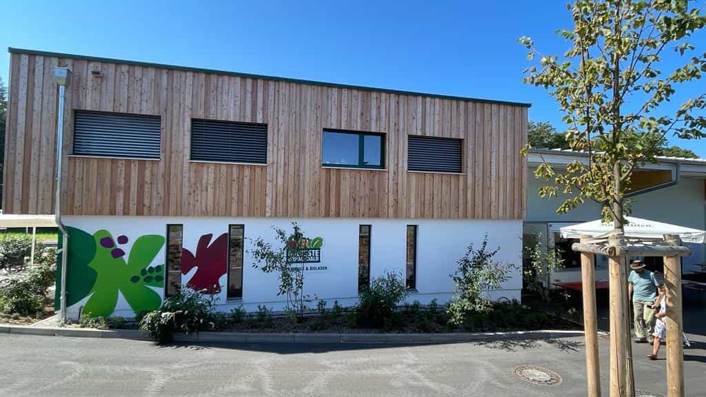 Frontansicht des Holzbaus der Ökokiste Donau-Wald mit Holzfassade und Bioladen-Eingang in Wiesenfelden