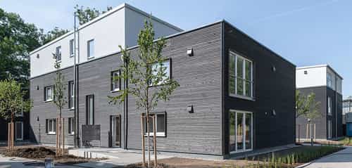 Wohnhaus mit dunkler Holzfassade und weißem Staffelgeschoss im Donau-Wohnpark, 34 Wohneinheiten von Haas