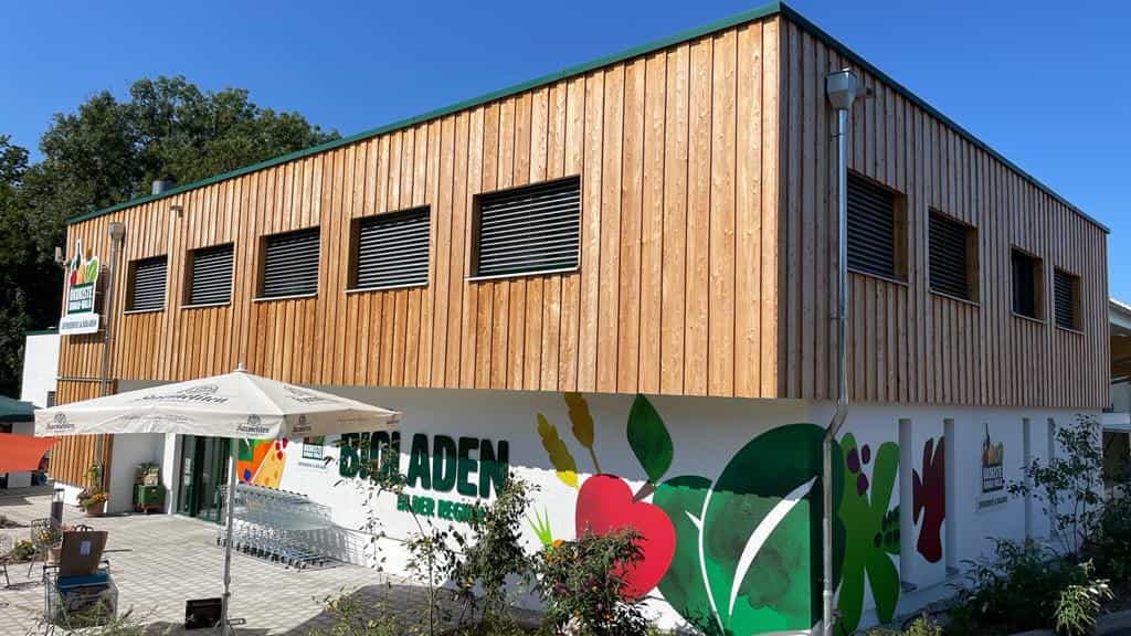 Neues Betriebsgebäude der Ökokiste Donau-Wald mit Bioladen-Schriftzug, Eckansicht des Holzbaus von Haas