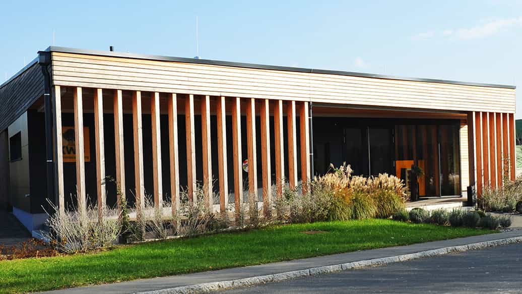 Ausstellungsgebäude von KWB mit Holzlamellenfassade und überdachtem Eingang von Haas Gewerbebau