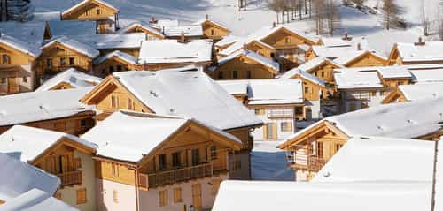 Blick über die verschneiten Chalet-Dächer der Ferienwohnanlage mit 205 Wohneinheiten in Pragelato